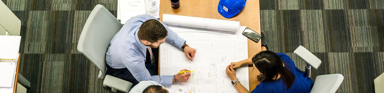 man and woman sitting at desk reviewing architecture plans